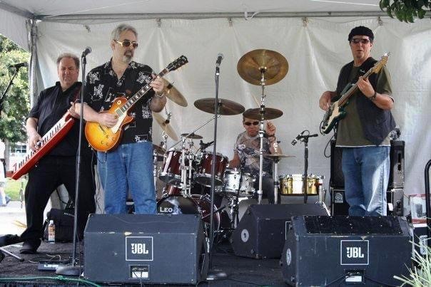 John Seppala performing with his band under an outdoor festival tent
